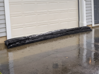 Flood barrier bags across a garage doorway in the rain